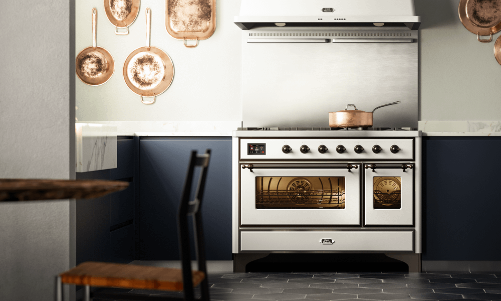 An Ilve Milano range cooker finished in white. Situated in a navy blue kitchen featuring copper pans.