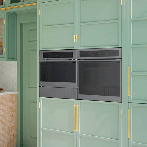 Built in appliances in green cabinetry, with a warming drawer shown under a microwave.