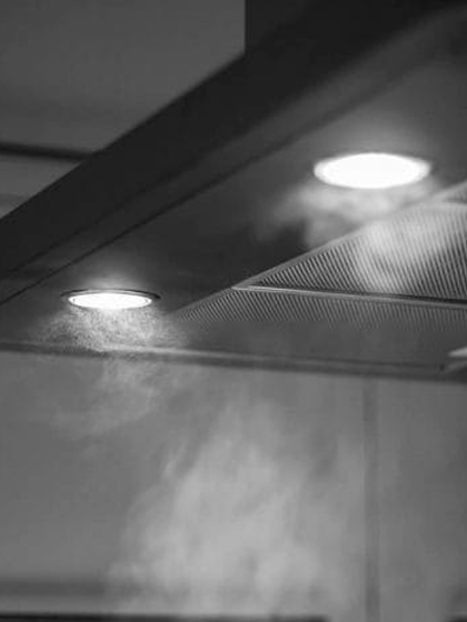 Black and white image of cooker hood lights illuminating the steam underneath