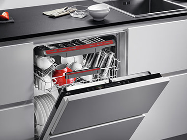 Opened AEG dishwasher, revealing it fully loaded with dishes.