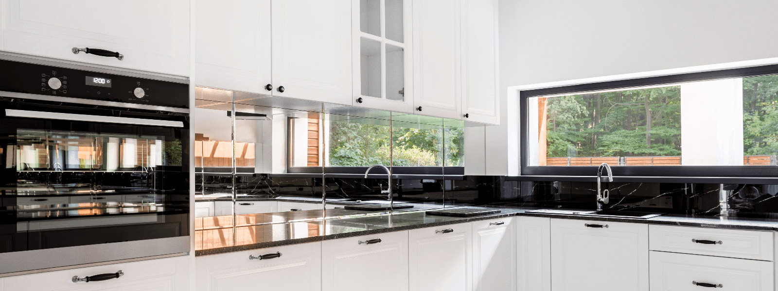 Black and white modern kitchen with mirror splashback and built-in oven.