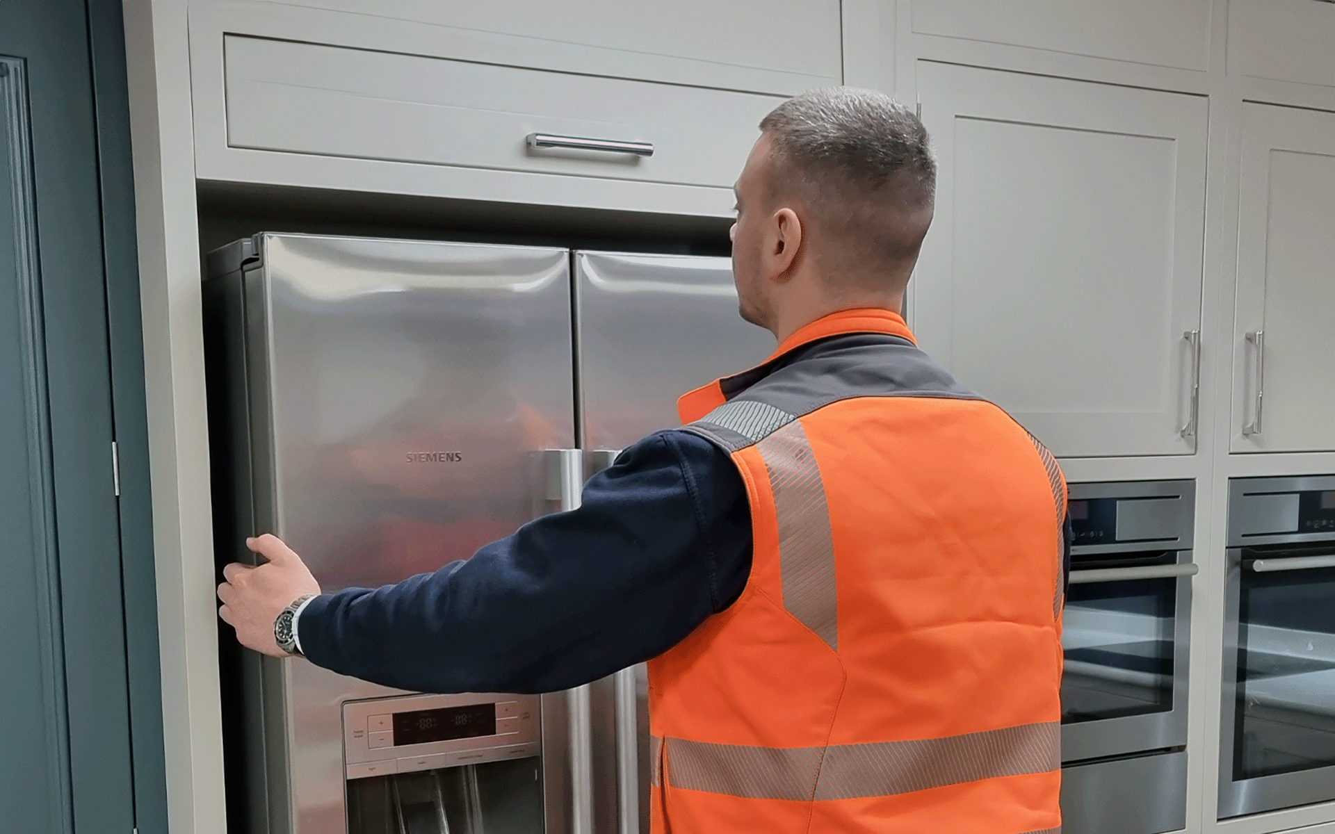 Man in orange hi-vis installing an American style Fridge Freezer
