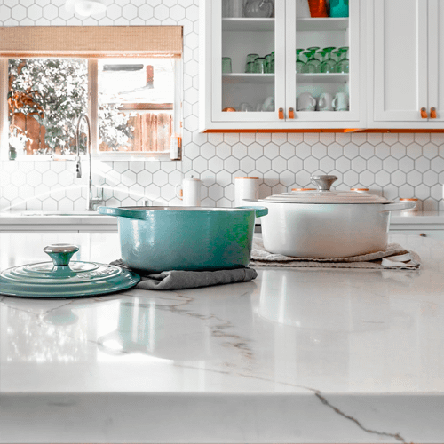 White marble counter with casserole dishes sitting on top under tea towels
