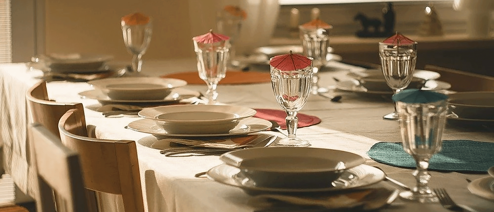 A dining table with a formal set-up, and little umbrellas in the glasses.