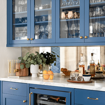 Blue kitchen cabinets. Integrated wine cooler is in bottom cabinets, and upper glass doors show glass storage.