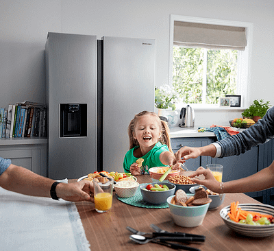 Family eating breakfast in front of Samsung American style fridge freezer