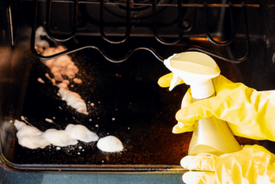 Spraying unbranded oven cleaner into oven