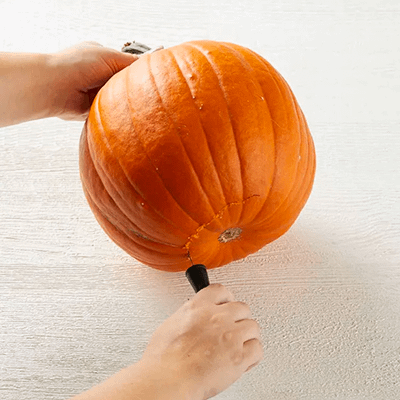 Person cutting into a pumpkin from the bottom