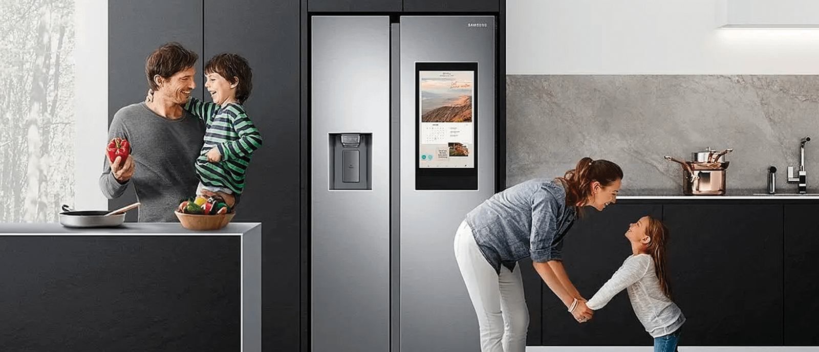 Happy family with two parents and two children in the kitchen with a Samsung Family Hub American Style Fridge Freezer.