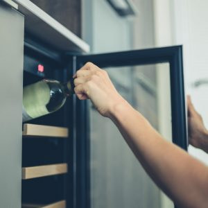 A person removing wine from a wine cooler