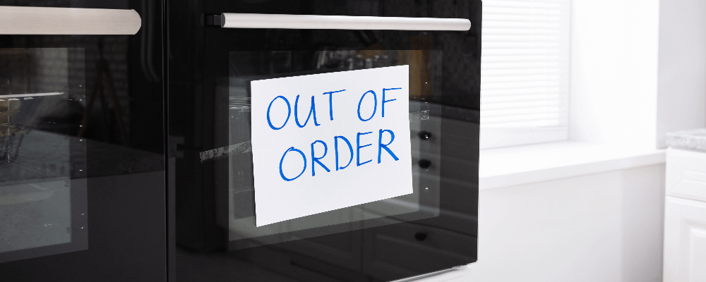 Built-in microwave with an "out of order" sign taped on the outside.