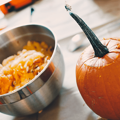 Pumpkin next to a bowl of pumpkin guts