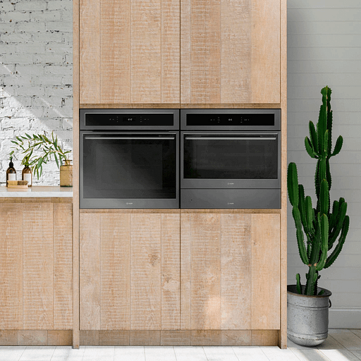 Built in microwave shown next to a built in oven in wooden cabinetry.