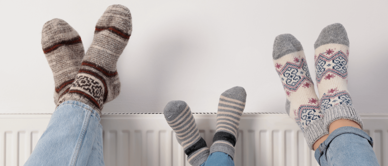 Family feet with winter socks warming on a radiator
