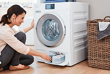 Lady opening the bottom of the washing machine to change the filter
