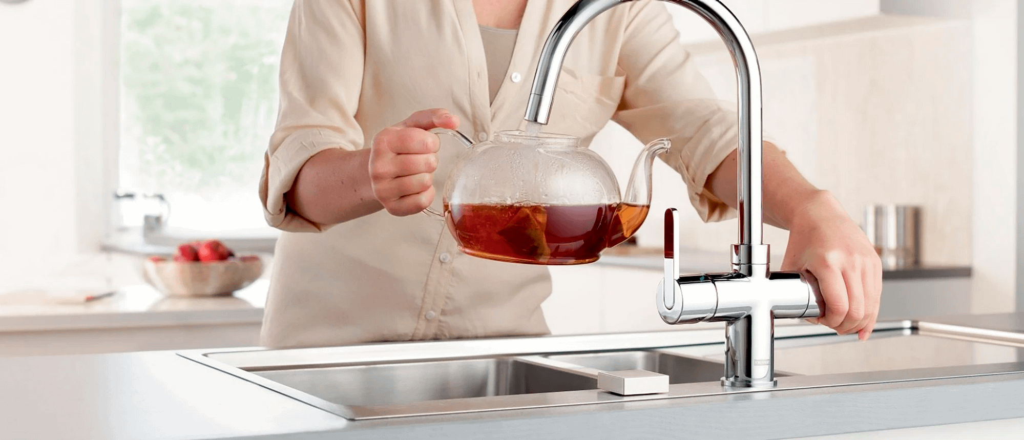 Person using a boiling water tap to fill a teapot up with hot water