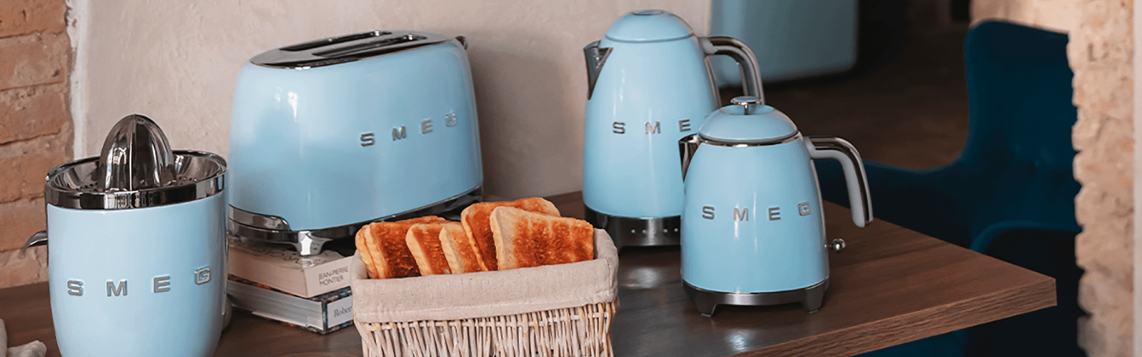 Smeg blue appliances including two kettles, a toaster and a juicer. A basket of toast is in front.