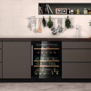 Wine cooler in between cabinet units with utensils hung above