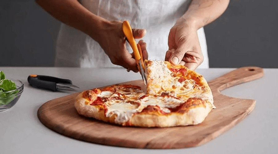 Using scissors to cut a pizza.