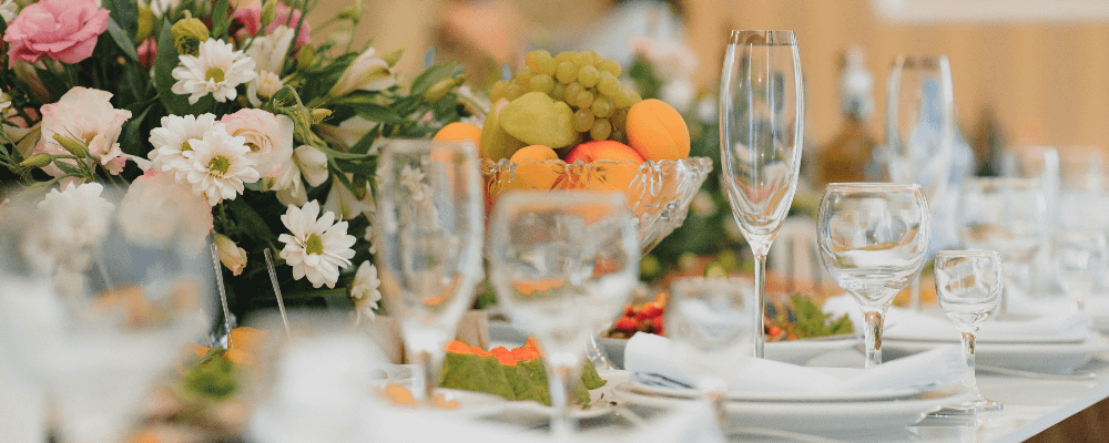 A close up of a formal dining set up, with a fresh fruit bowl in the centre and in focus.