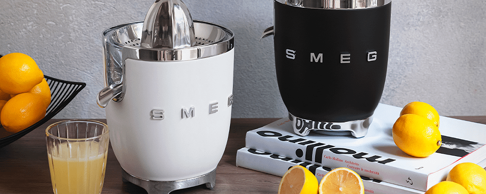 Black and white Smeg juicers making lemon juice, surrounded in lemons.