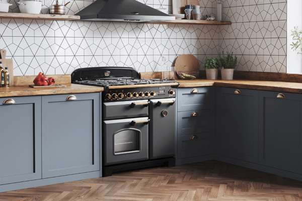 A charcoal black Rangemaster range cooker in a kitchen with blue cabinetry 