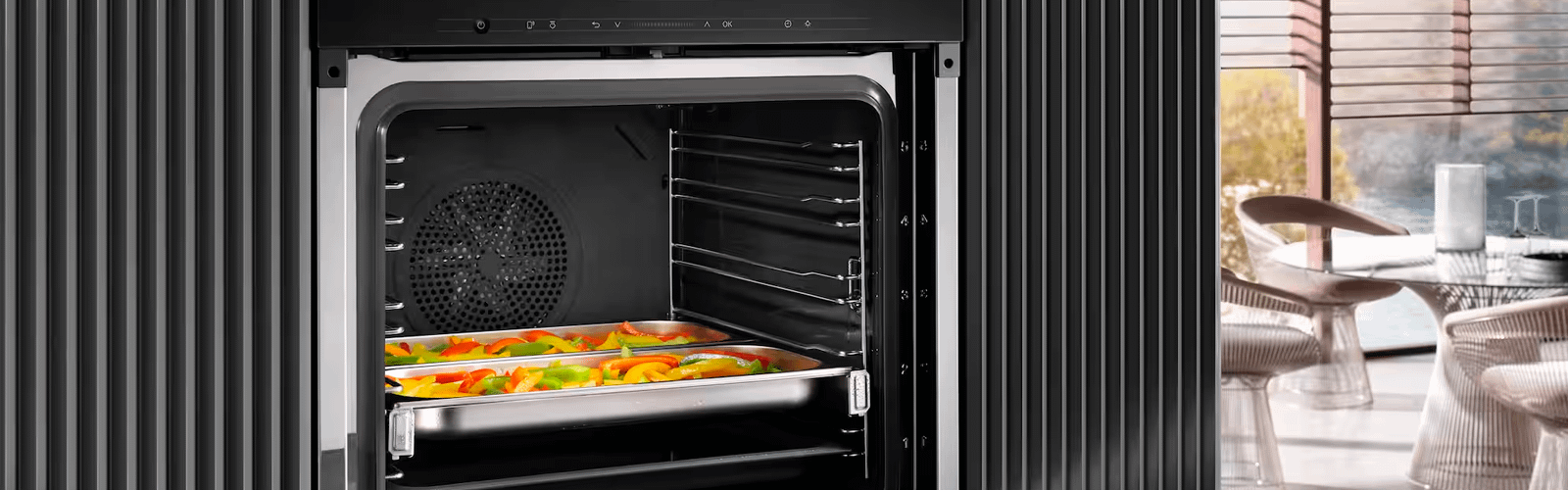 Open Miele oven with raw chopped bell peppers in trays inside.