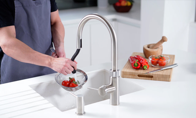 The Quooker Flex boiling water tap with the hose extended washing tomatoes in a sink.