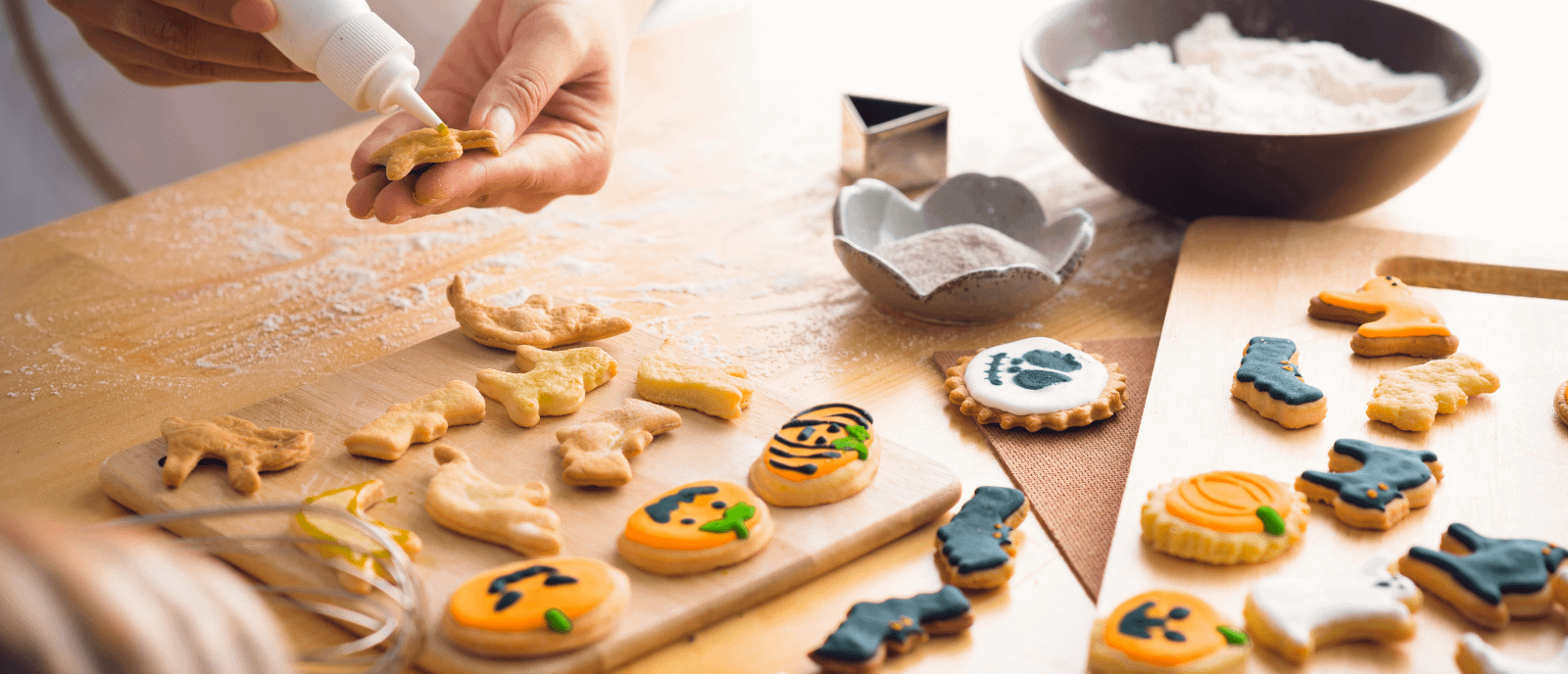 Person piping Halloween designs onto homemade biscuits.