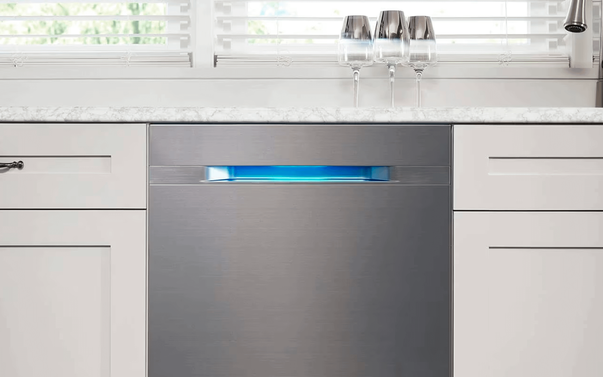 Built in Samsung dishwasher in white kitchen with blue glow from handle.