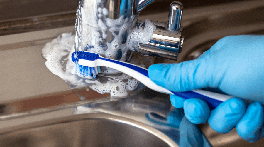 Using toothbrush to clean tap