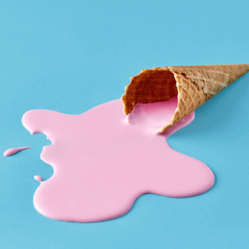 Ice cream cone on the floor with pink melted ice cream spilling out. Against a solid blue background.