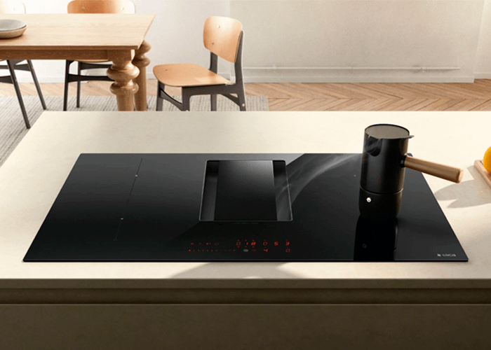 An Elica NikolaTesla Alpha extraction hob featuring a minimalistic design. Steam from an induction hob stove top kettle is being drawn in from the right side.