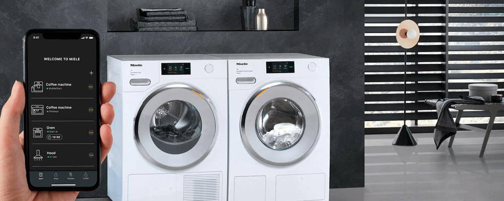 Person using Miele@home app to control laundry machines.
