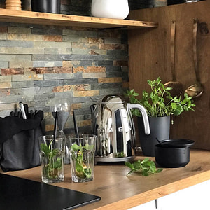 Stainless steel Smeg kettle on a kitchen counter next to a pot of herbs.