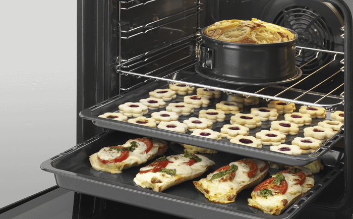 An image of AEG's SteamBake Multifunction Single Oven open displaying an array of different foods 