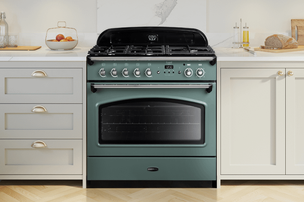 A Rangemaster mineral green dual fuel range cooker in a neutral setting kitchen