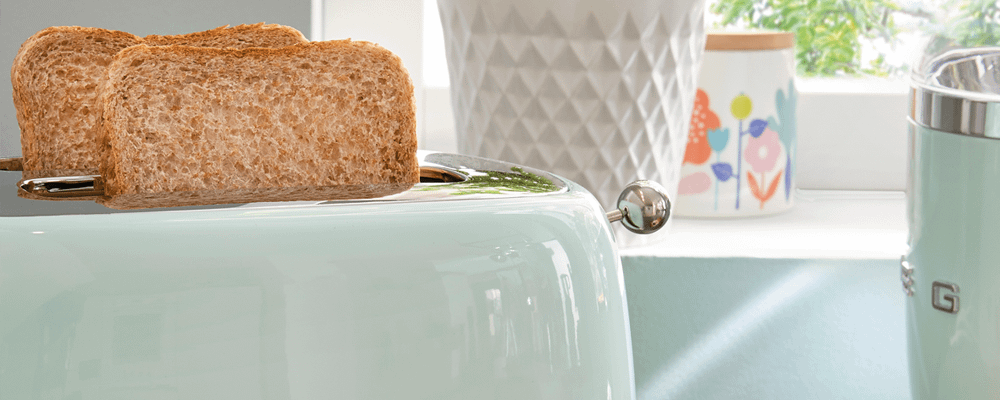 Toast sticking out of a mint green Smeg toaster