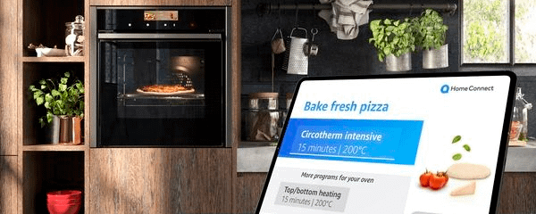 Neff oven cooking a pizza in the background, with a screen showing the process of the cook on the Home Connect app in the foreground.