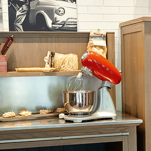 Red Smeg stand mixer sitting on counter with spaghetti nests 
