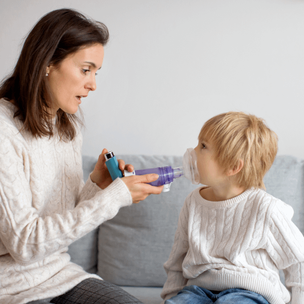 Woman helping child use an inhaler for asthma