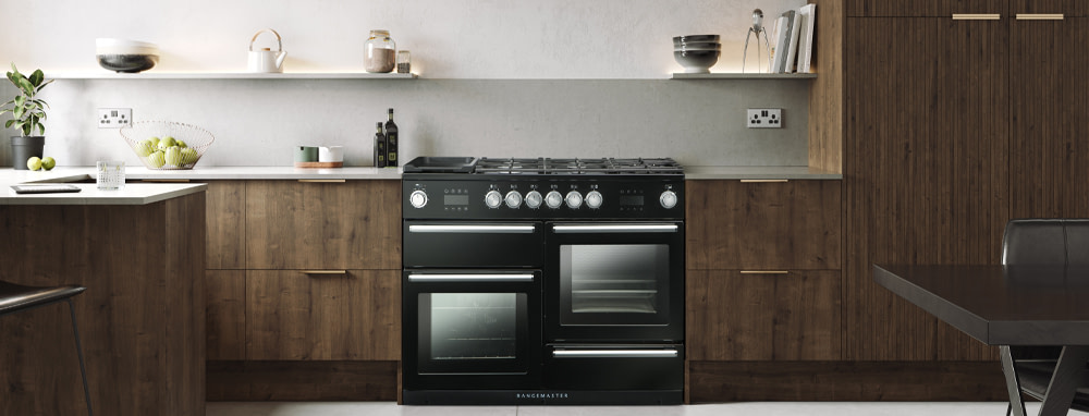 A black Rangemaster range cooker in kitchen with dark wooden cabinetry. 