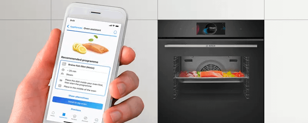 Bosch oven cooking salmon, with person using the Home Connect app on their phone for oven assistance. 