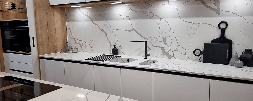 White kitchen with marble countertops and splashback. Matte black features such a tap.