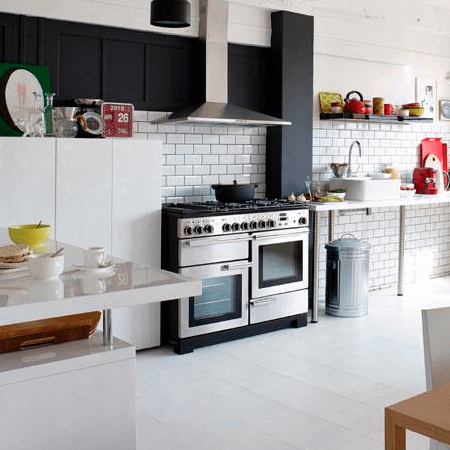 A Rangemaster Professional Deluxe 110cm range cooker in silver, in a a modern black and white kitchen.