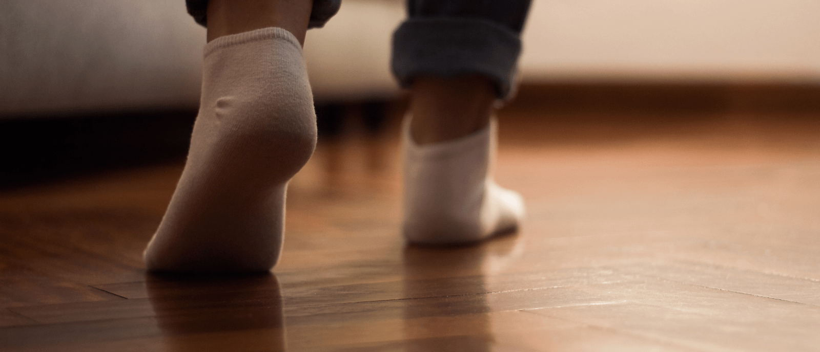 Person walking on wooden floor, whilst wearing socks. 