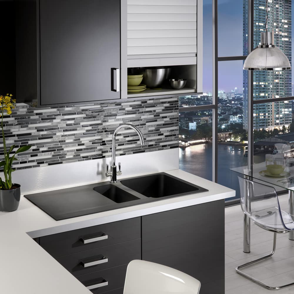 franke-OID651-1000x1000 A Franke Orion tectonite sink finished in black. Positioned in a modern black and white kitchen in an apartment overlooking a city scape.