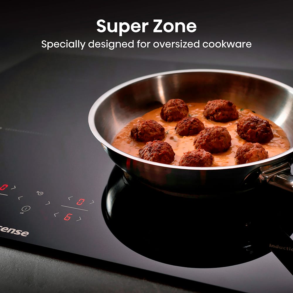 Super Zone_HI6401BSC_5 Large frying pan cooking meatballs on the Super Zone of a Hisense hob, a zone specially designed for oversized cookware.