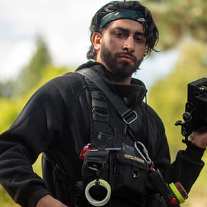 Riaz wearing our LED Chest Rig on a film set with gaffer tape attachments and holding a film camera