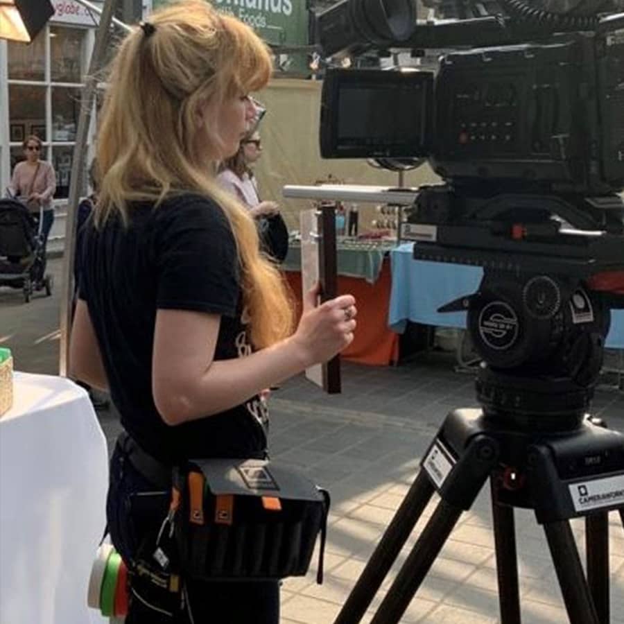 Camera assistant Bianka on set with a gaffer tape attachment and Dirty Rigger comfort fit gloves, gaffer tape and AC bag